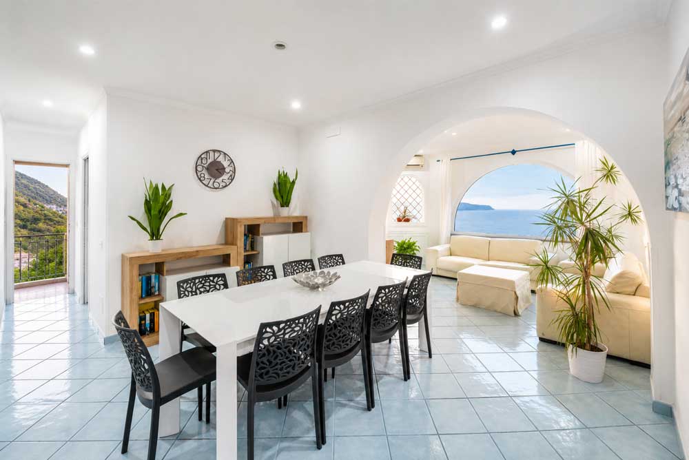 Sala da pranzo luminosa con arco e vista mare a Massa Lubrense